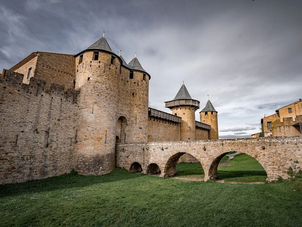 The Château Comtal's round towers and conical roofs above the arched stone bridge across its dry ditch, Carcassonne