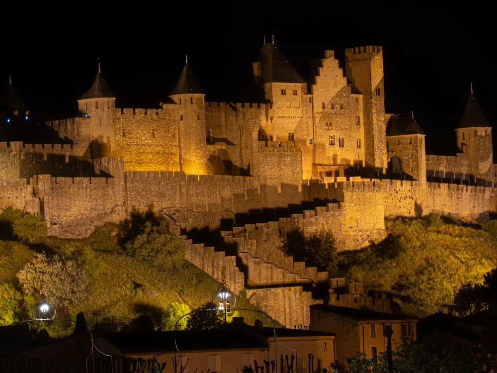 The walls and towers of the Cité de Carcassonne lit up at night on their hill